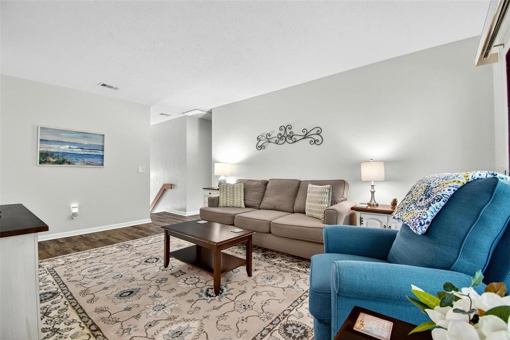 A living room features a brown sofa, a blue armchair, and a patterned area rug — 8 MID OAKS CIRCLE UNIT 8, PALM COAST, FL