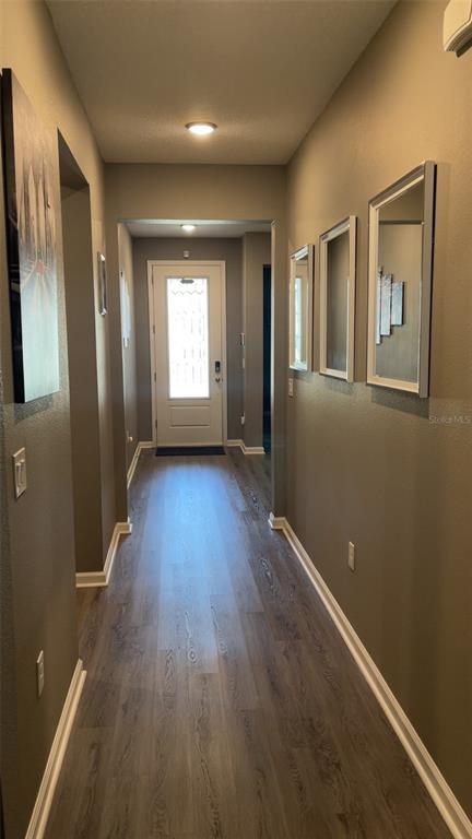 A living room features a dark sofa, a television, a window with blinds, and wall decor — 5306 MEADOW SONG DRIVE, OKAHUMPKA, FL