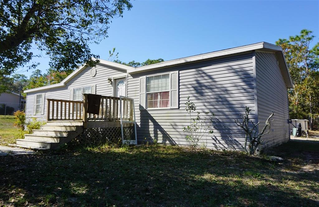A single-story manufactured home with gray vinyl siding and a wooden front deck — 5012 S ORWELL POINT, HOMOSASSA, FL
