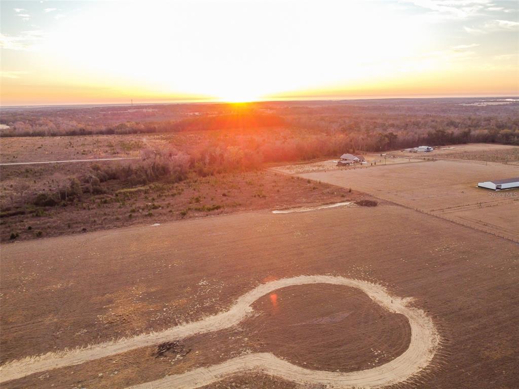An aerial view shows a dirt cul-de-sac in a large, open field at sunset — 4178 ROYAL SKY (LOT 8 ) COURT, BROOKSVILLE, FL