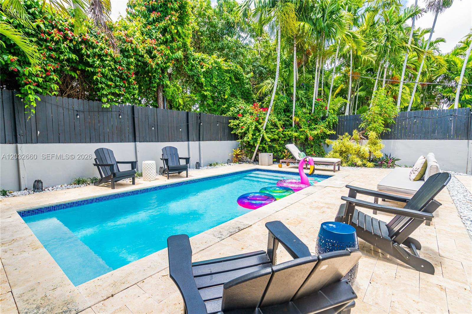 A backyard features a rectangular swimming pool, lounge chairs, and black Adirondack chairs on a patio — 520 SW 22 rd, Miami FL 33129, MIAMI, FL