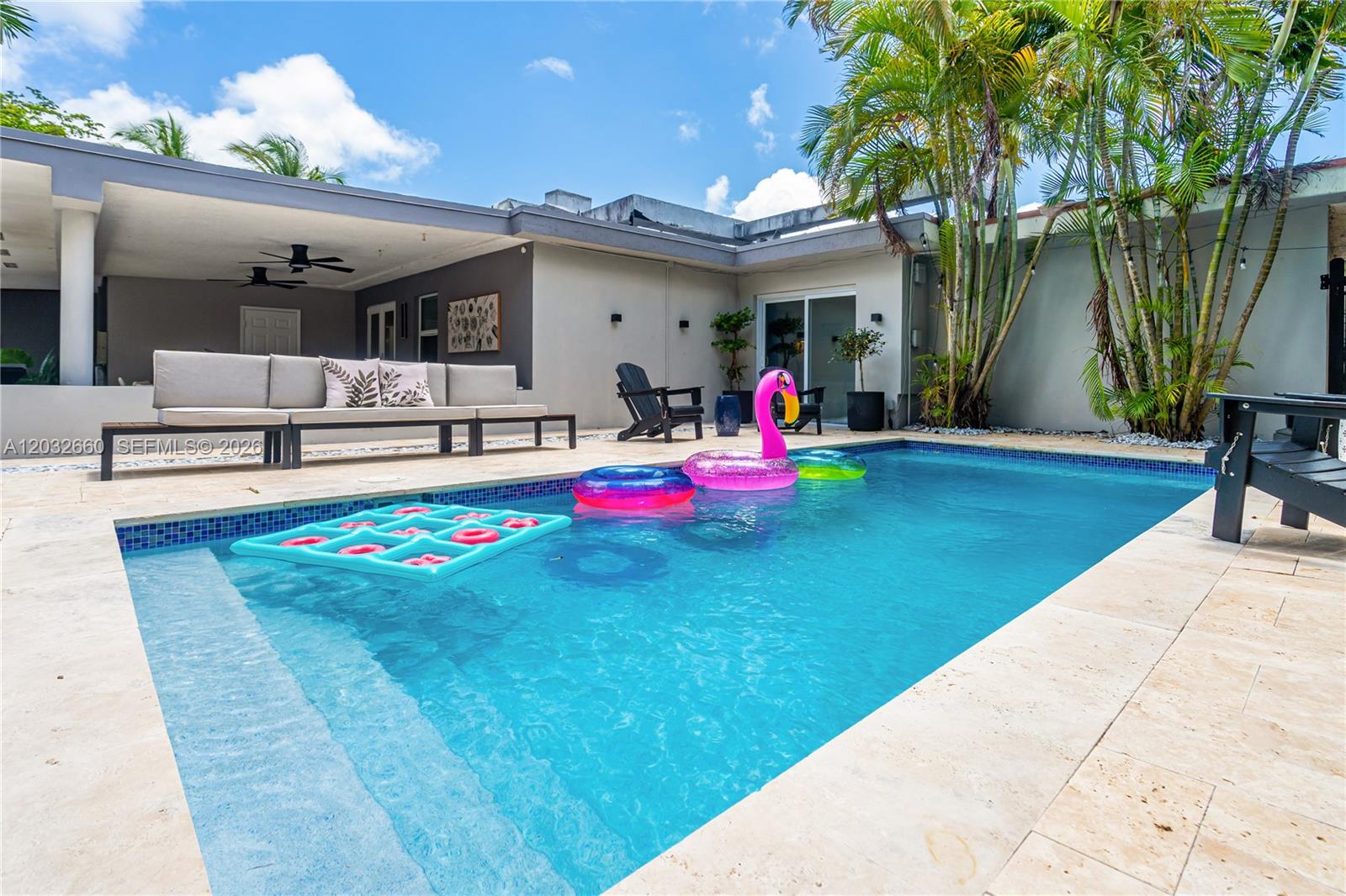 A swimming pool with floating inflatables sits in a backyard patio area with outdoor seating — 520 SW 22 rd, Miami FL 33129, MIAMI, FL