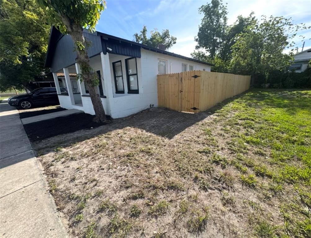 A white house with black trim features a wooden fence and a large side yard — 715 JERNIGAN AVENUE, ORLANDO, FL