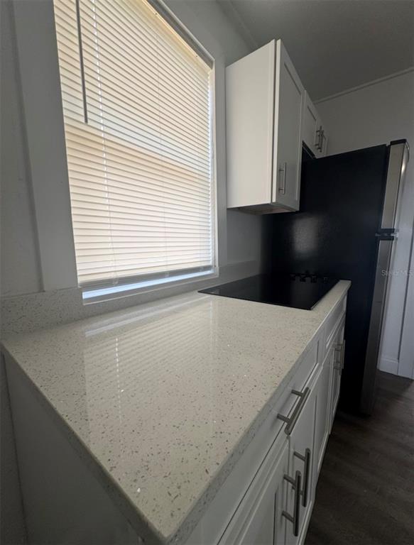 A kitchen features white cabinets, speckled quartz countertops, a black cooktop, and a window — 715 JERNIGAN AVENUE, ORLANDO, FL