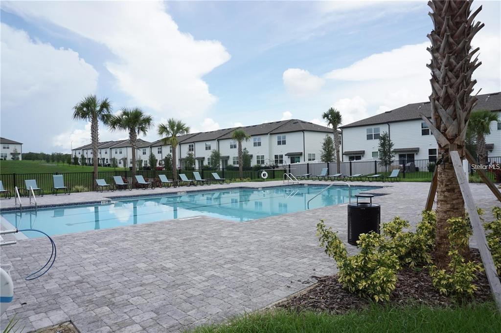 A rectangular swimming pool is surrounded by a paved deck, lounge chairs, and residential buildings — 342 MADISON DRIVE, DAVENPORT, FL
