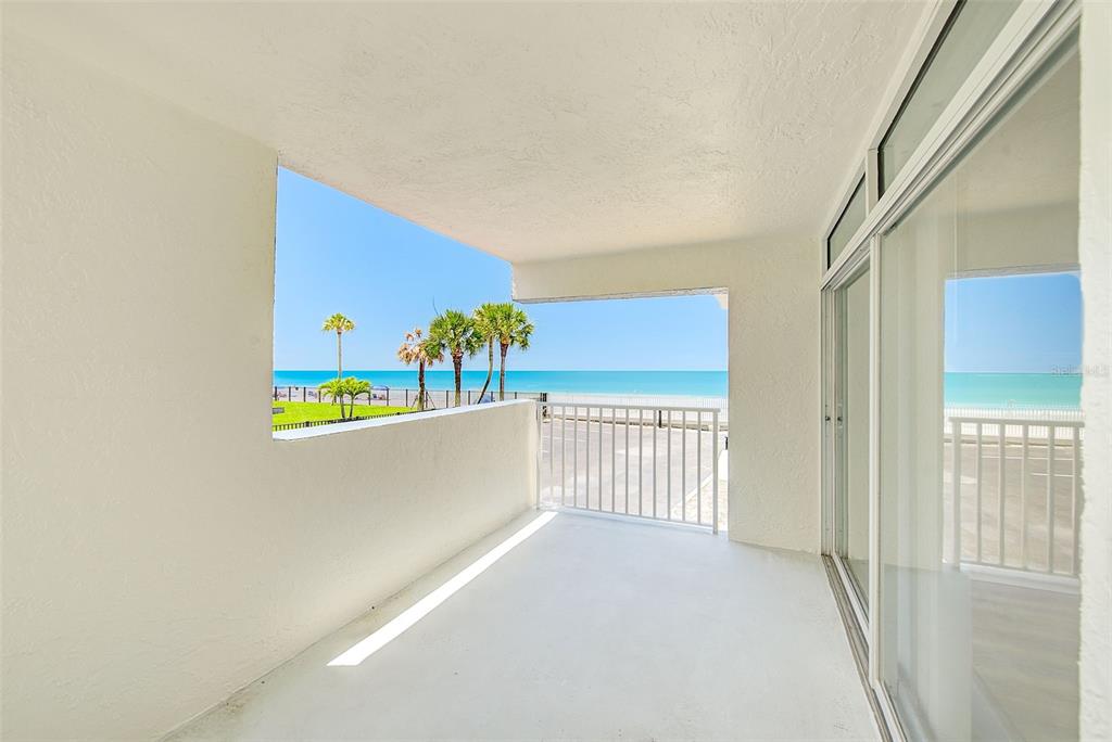 A white balcony overlooks a beach with palm trees and the ocean — 16308 GULF BOULEVARD UNIT 103, REDINGTON BEACH, FL