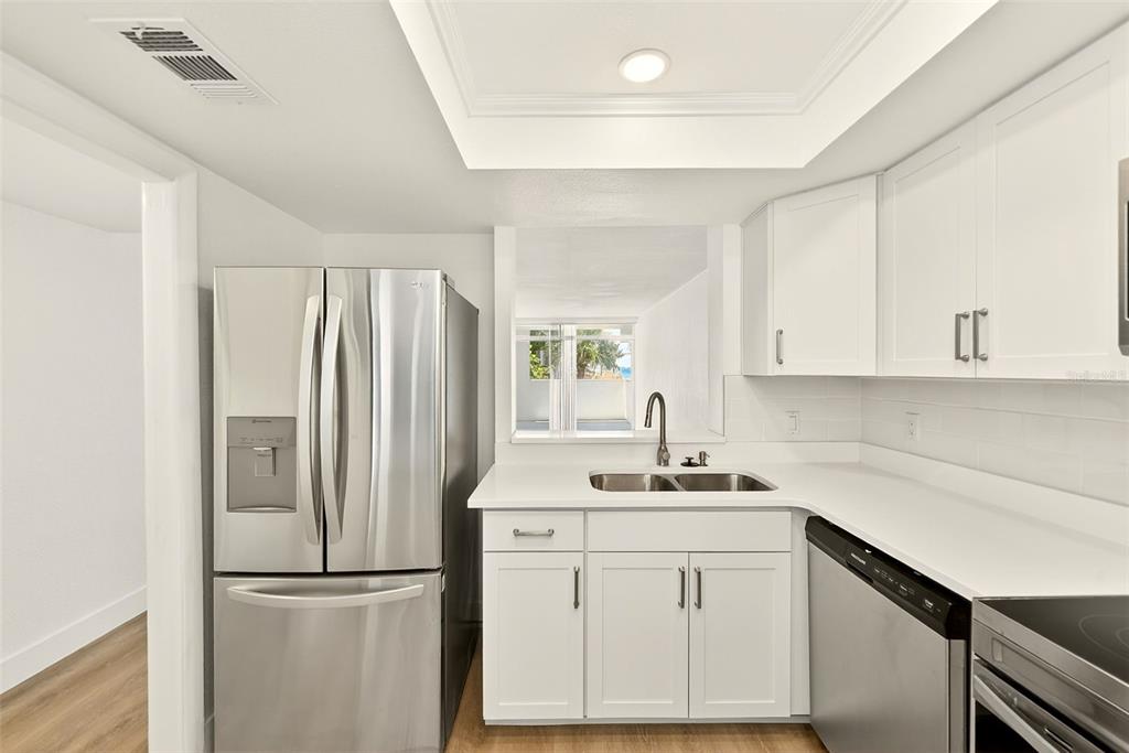 A kitchen features white cabinets, stainless steel appliances, a double sink, and light countertops — 16308 GULF BOULEVARD UNIT 103, REDINGTON BEACH, FL