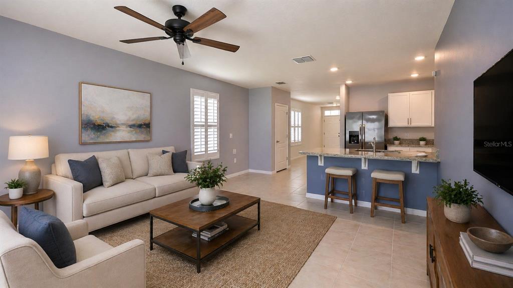 A living room with a sofa, coffee table, and breakfast bar kitchen in an open layout — 349 CARYOTA COURT, NEW SMYRNA BEACH, FL