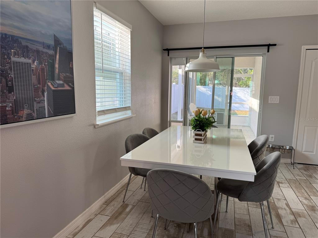 A dining room features a white table, grey upholstered chairs, tile flooring, and sliding glass doors — 118 HURST CT, DELAND, FL