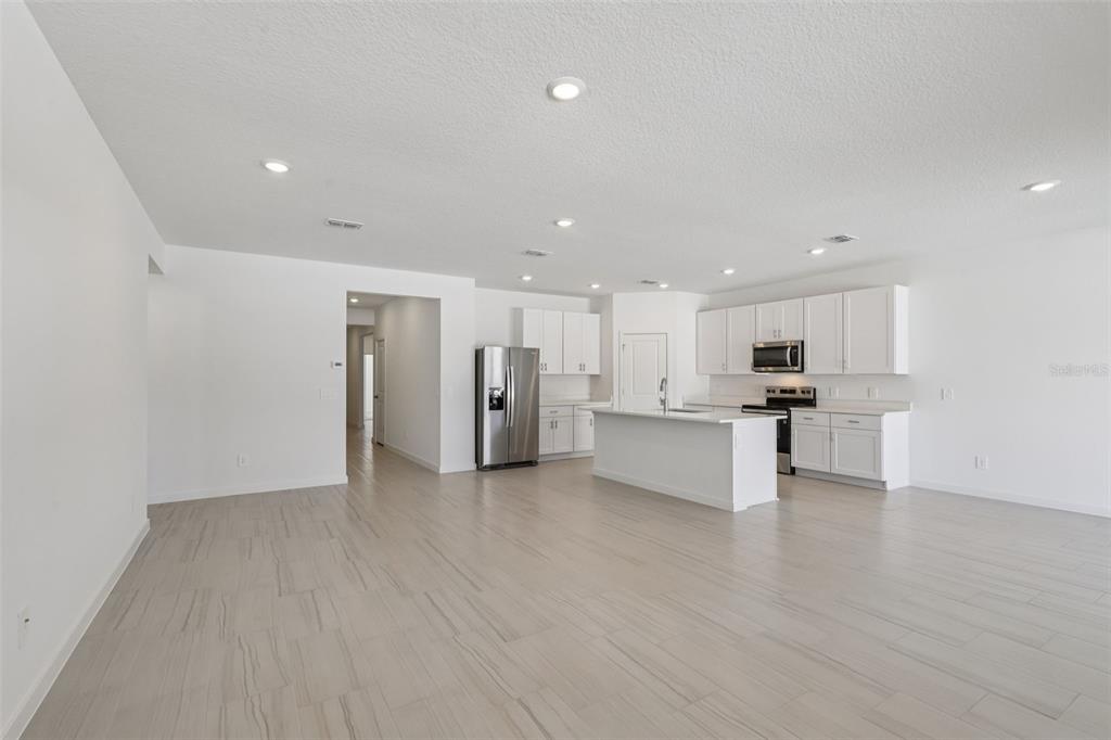An open-concept kitchen and living area featuring white cabinetry, a center island, and tile flooring — 84 WANDERING CREEK WAY, PALM COAST, FL