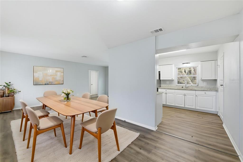 A dining area with a wooden table and chairs sits adjacent to a white kitchen — 170 W CRYSTAL LAKE AVENUE, LAKE MARY, FL
