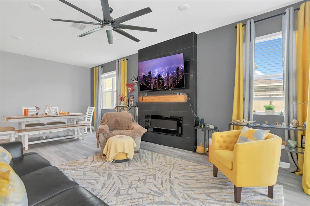 A living room features a black tiled fireplace, a mounted television, and yellow accent chairs — 6213 DOLOSTONE DRIVE, LAKELAND, FL