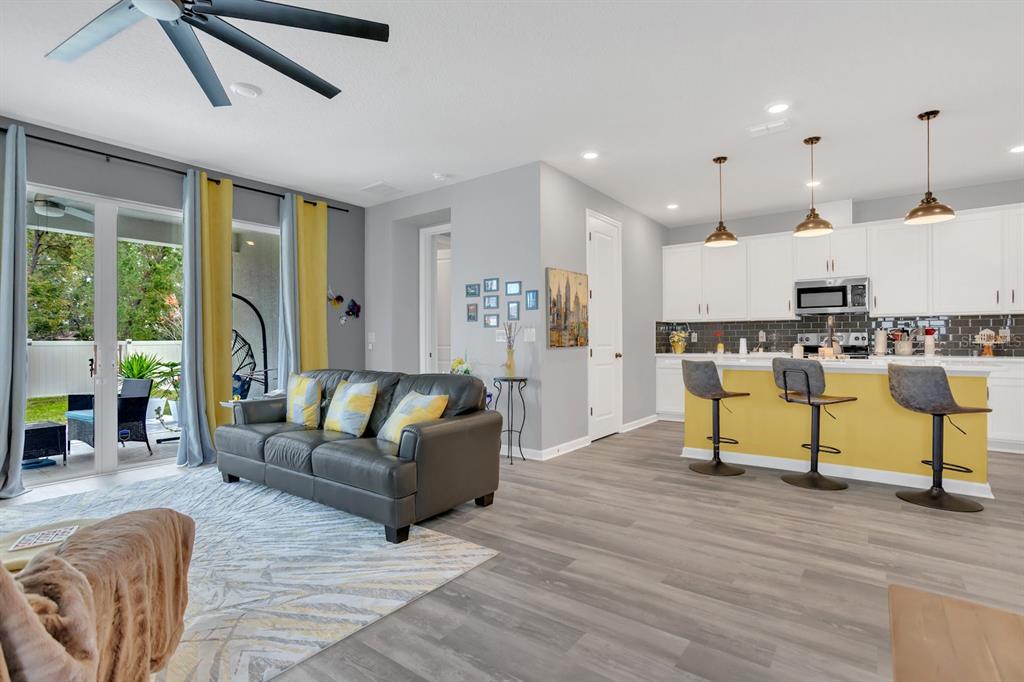 An open-concept living room and kitchen with gray flooring, a yellow island, and sliding doors — 6213 DOLOSTONE DRIVE, LAKELAND, FL