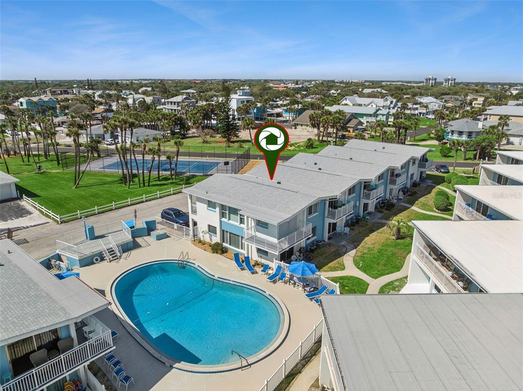 An aerial view shows a multi-story apartment building with a swimming pool and tennis court — 513 N ATLANTIC AVENUE UNIT 33, NEW SMYRNA BEACH, FL