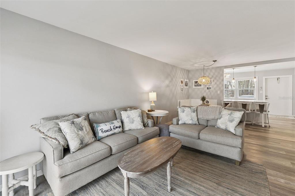 A living room features two gray sofas, a wooden coffee table, and light wood flooring — 513 N ATLANTIC AVENUE UNIT 33, NEW SMYRNA BEACH, FL