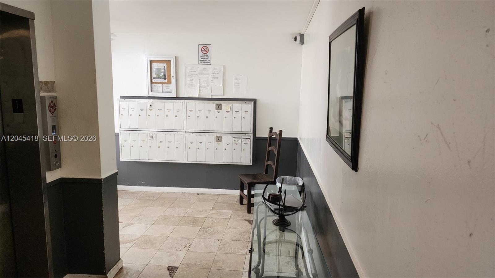An indoor mailroom features a wall of metal mailboxes, a chair, and a glass table — 1075 93rd St # 304, Bay Harbor Islands FL 33154, BAY HARBOR ISLANDS, FL