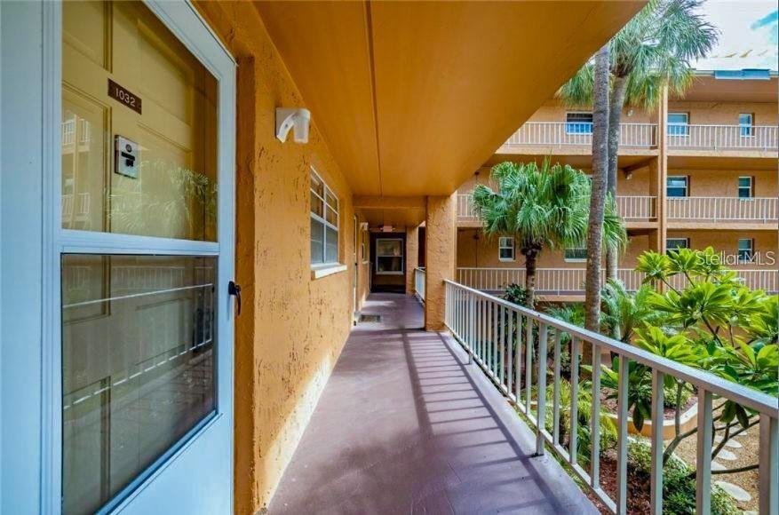 An exterior walkway leads to a unit door with a view of a courtyard — 12760 INDIAN ROCKS ROAD UNIT 1031, LARGO, FL