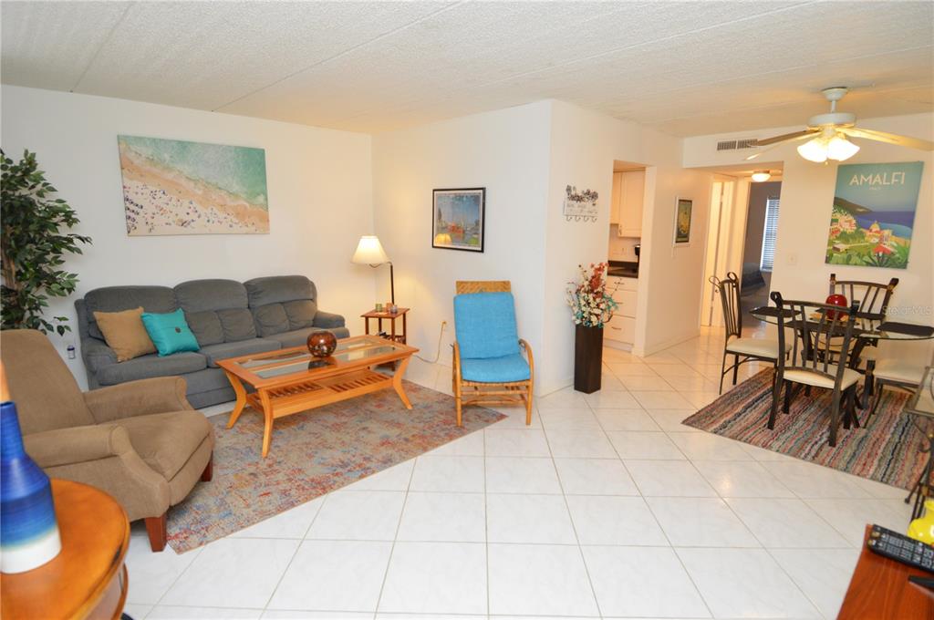 A living and dining area with tile floors, a blue sofa, and a dining set — 12760 INDIAN ROCKS ROAD UNIT 1031, LARGO, FL