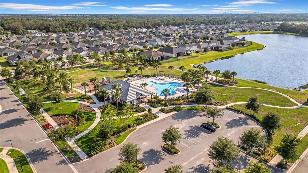 A beige townhome with a single-car garage, a concrete driveway, and palm trees in front — 11728 CAMBIUM CROWN DRIVE, RIVERVIEW, FL