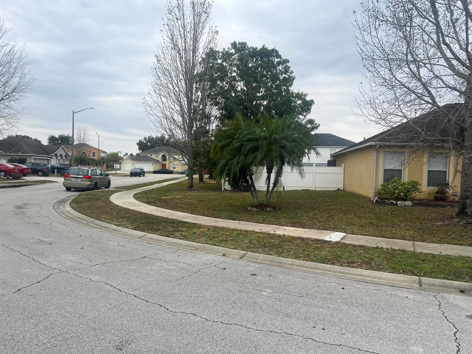 A residential street corner features a yellow house, a palm tree, and parked cars — 5091 Plymouth Turtle Circle, FL 34772, FL