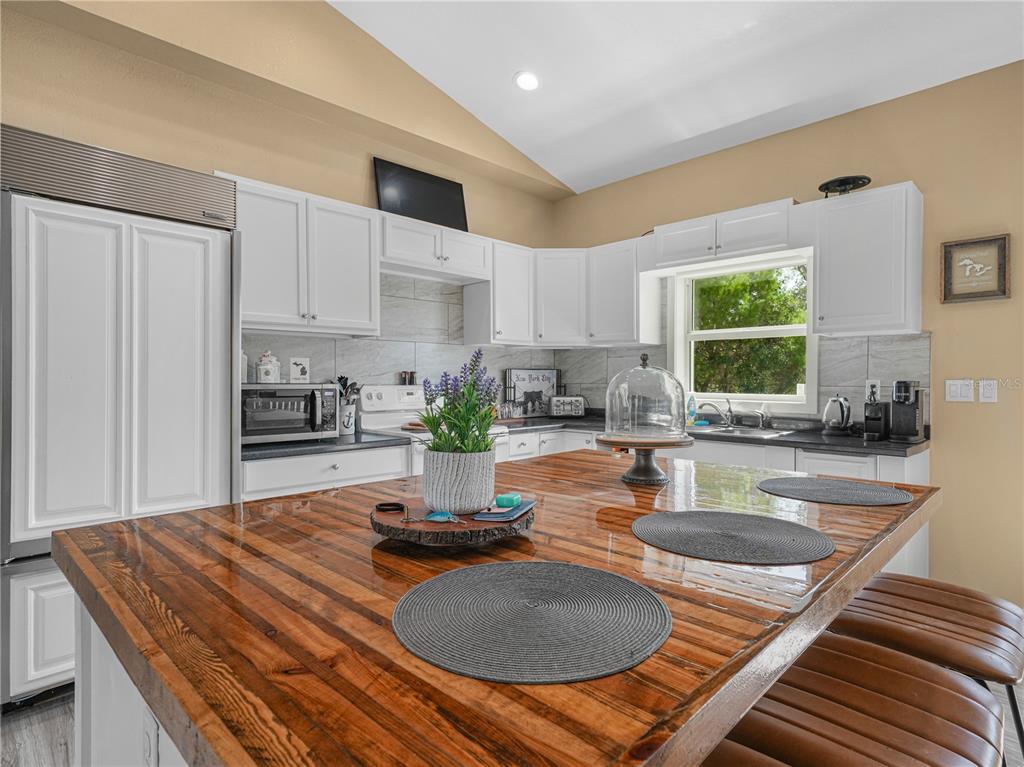 A kitchen features white cabinets, a butcher block island, and a stainless steel refrigerator — 10134 S ORANGE BLOSSOM BOULEVARD, SEBRING, FL