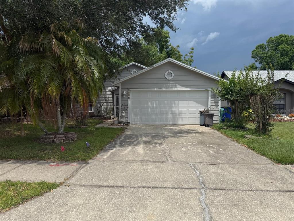 A single-story house with light gray siding, a two-car garage, and a concrete driveway — 4100 NATCHEZ TRACE DRIVE, ST CLOUD, FL