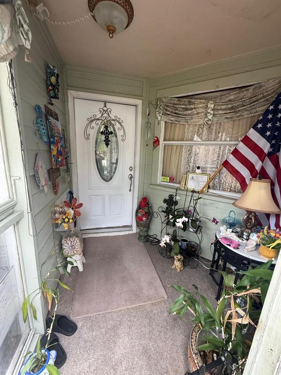 A covered porch features a white front door, a large American flag, and potted plants — 4100 NATCHEZ TRACE DRIVE, ST CLOUD, FL