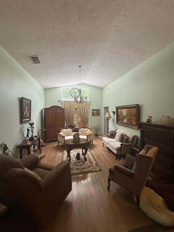 A living room features vaulted ceilings, light green walls, wood flooring, and traditional furniture — 4100 NATCHEZ TRACE DRIVE, ST CLOUD, FL
