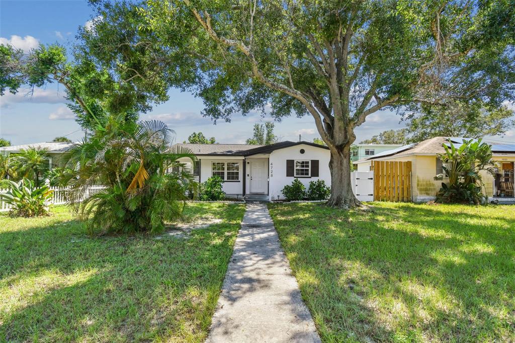 A single-story house with a white exterior, a front walkway, and a large shade tree — 4728 9TH AVENUE N, ST PETERSBURG, FL