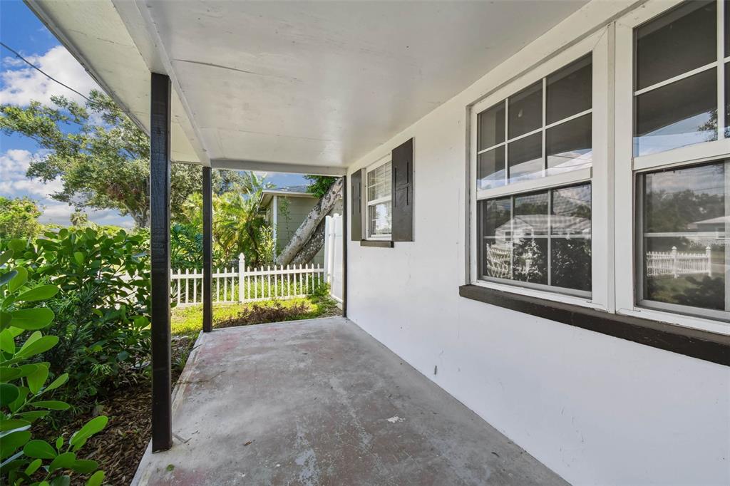 A covered concrete porch features white exterior walls, dark window shutters, and a white picket fence — 4728 9TH AVENUE N, ST PETERSBURG, FL