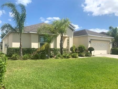 A single-story house with a beige exterior, a two-car garage, and palm trees in front — 406 WINDBOURNE WAY, HAINES CITY, FL