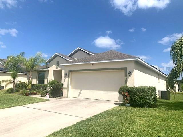A single-story house with a beige exterior, a two-car garage, and a concrete driveway — 406 WINDBOURNE WAY, HAINES CITY, FL