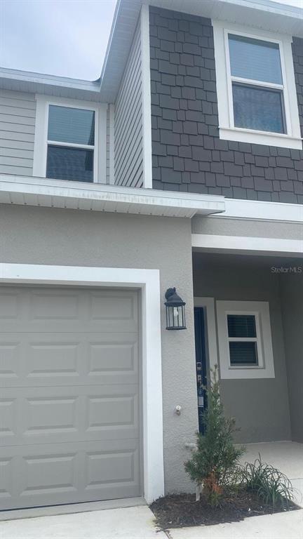 The exterior of a two-story house features a garage, gray siding, and dark shingle accents — 3606 MAYFAIR STREET, KISSIMMEE, FL