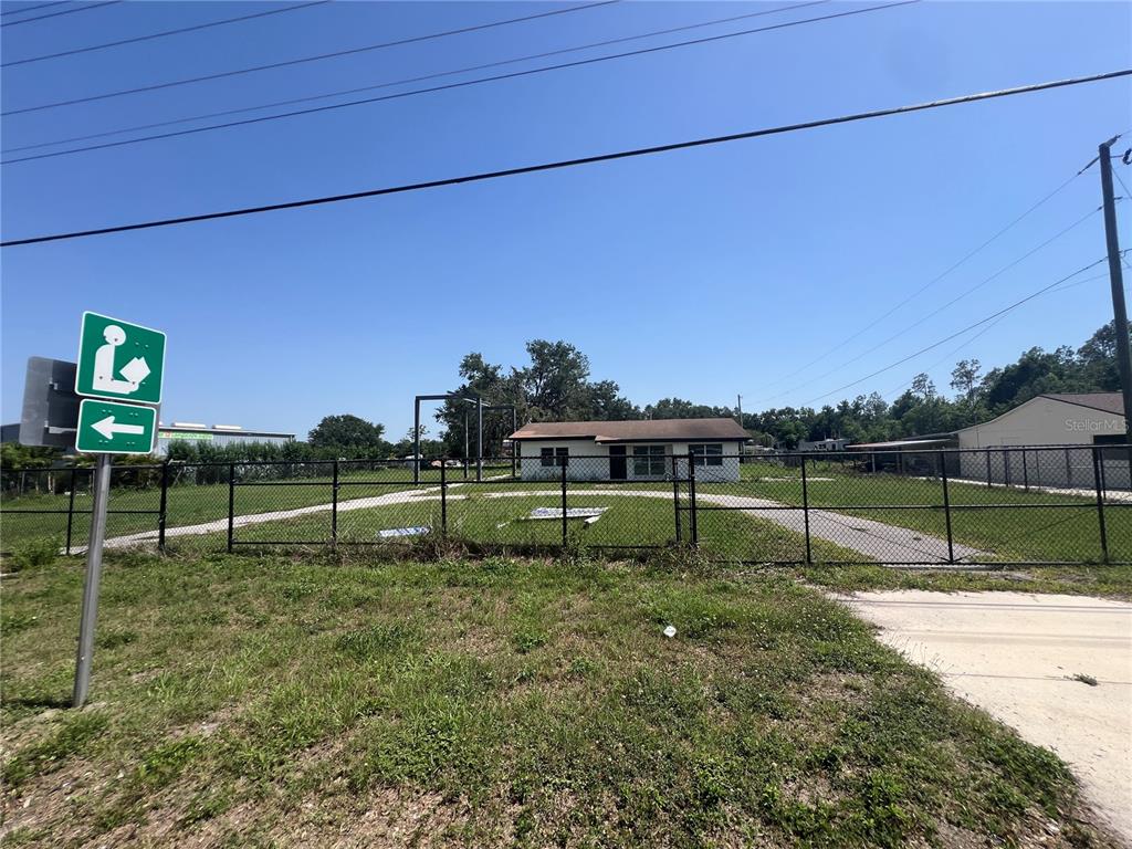A single-story house sits behind a chain-link fence on a grassy lot — 34020 & 34024 STATE ROAD 54, WESLEY CHAPEL, FL