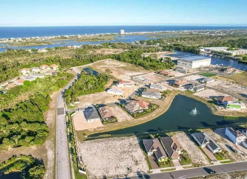 An aerial view shows a residential neighborhood under construction near a pond and the ocean — 87 DEL PALMA DRIVE, PALM COAST, FL