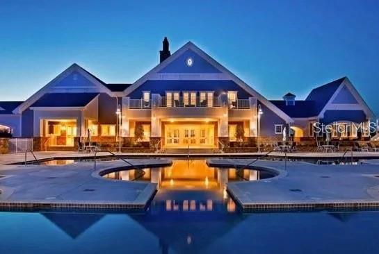 A large blue house with a swimming pool in the foreground at dusk — 87 DEL PALMA DRIVE, PALM COAST, FL