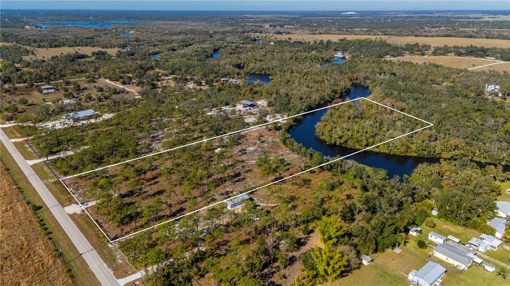 An aerial view shows a rectangular plot of land bordered by a road and a river — 36051 WASHINGTON LOOP ROAD, PUNTA GORDA, FL