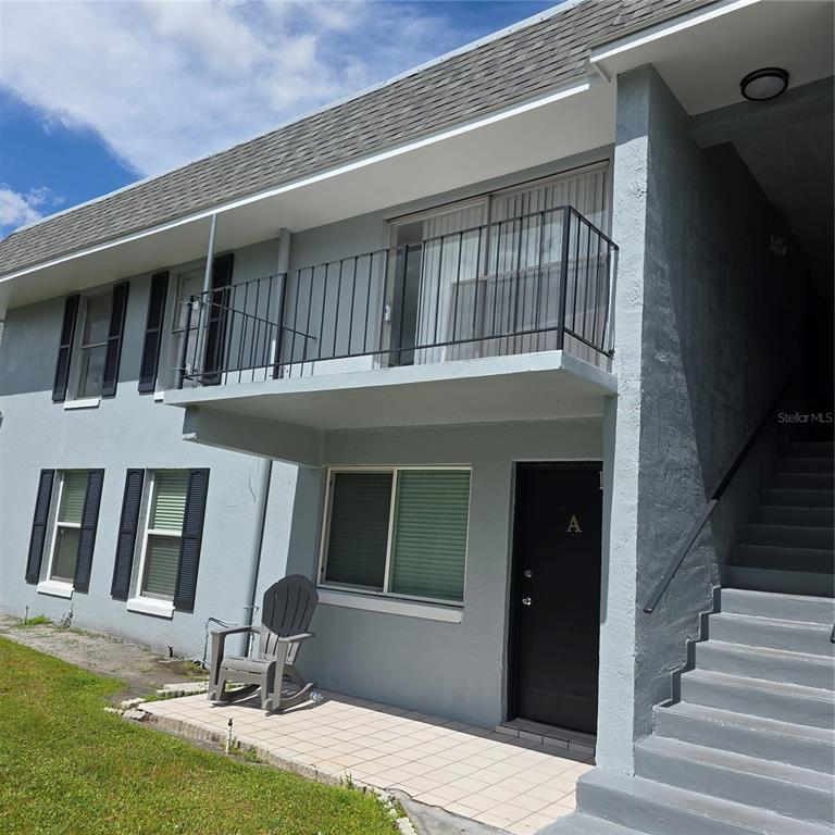 The exterior of a two-story apartment building features a ground-level patio and an upper balcony — 921 W OAK RIDGE ROAD UNIT C, ORLANDO, FL