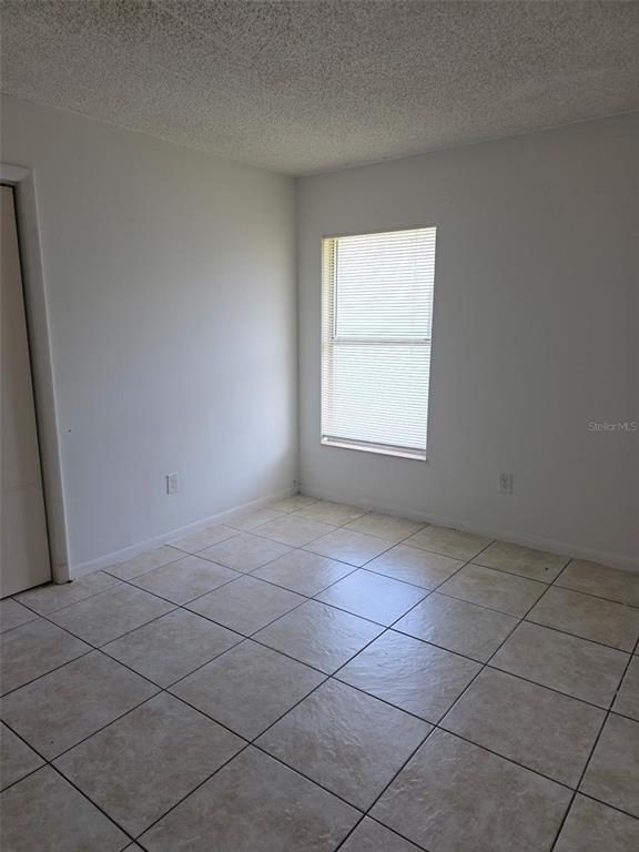 An empty room features white walls, a single window with blinds, and light-colored tile flooring — 921 W OAK RIDGE ROAD UNIT C, ORLANDO, FL