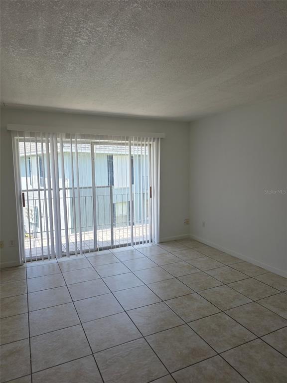 A room with light-colored tile flooring, white walls, and a sliding glass door with blinds — 921 W OAK RIDGE ROAD UNIT C, ORLANDO, FL