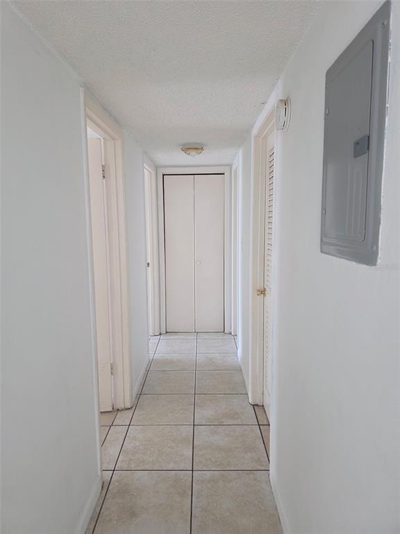 A narrow hallway with white walls, tiled flooring, and several closed doors — 921 W OAK RIDGE ROAD UNIT C, ORLANDO, FL