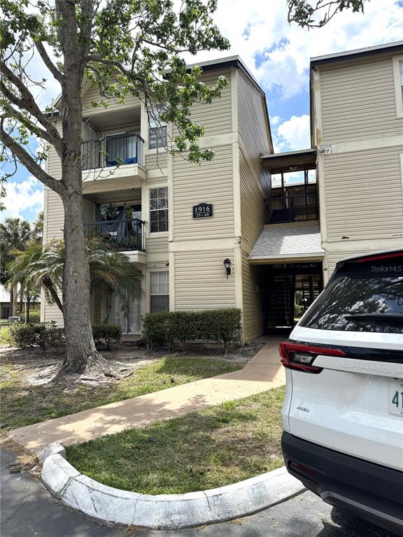 A three-story apartment building with beige siding and a white car parked in front — 1916 LAKE ATRIUMS CIRCLE UNIT 32, ORLANDO, FL