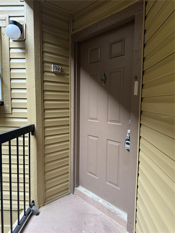 A brown front door with a number 32 plaque and a lockbox on the handle — 1916 LAKE ATRIUMS CIRCLE UNIT 32, ORLANDO, FL