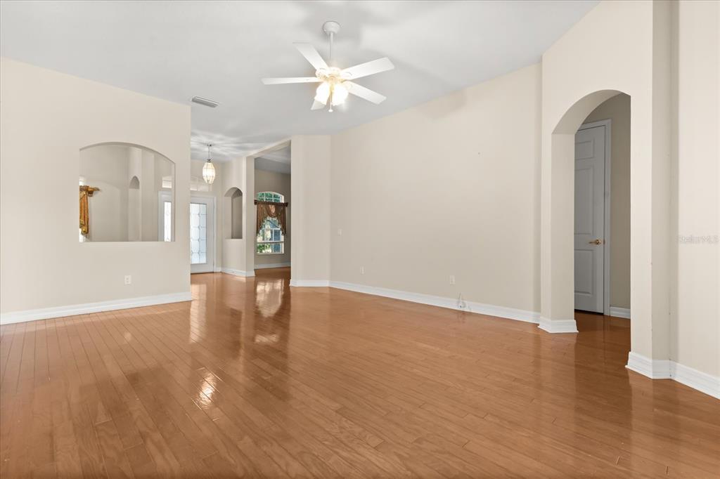 An empty room with light-colored walls, hardwood flooring, a ceiling fan, and arched doorways — 19027 DOVE CREEK DRIVE, TAMPA, FL
