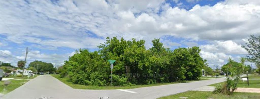 A vacant, tree-covered corner lot sits at the intersection of two paved residential streets — 501 E TARPON BOULEVARD NW, PORT CHARLOTTE, FL