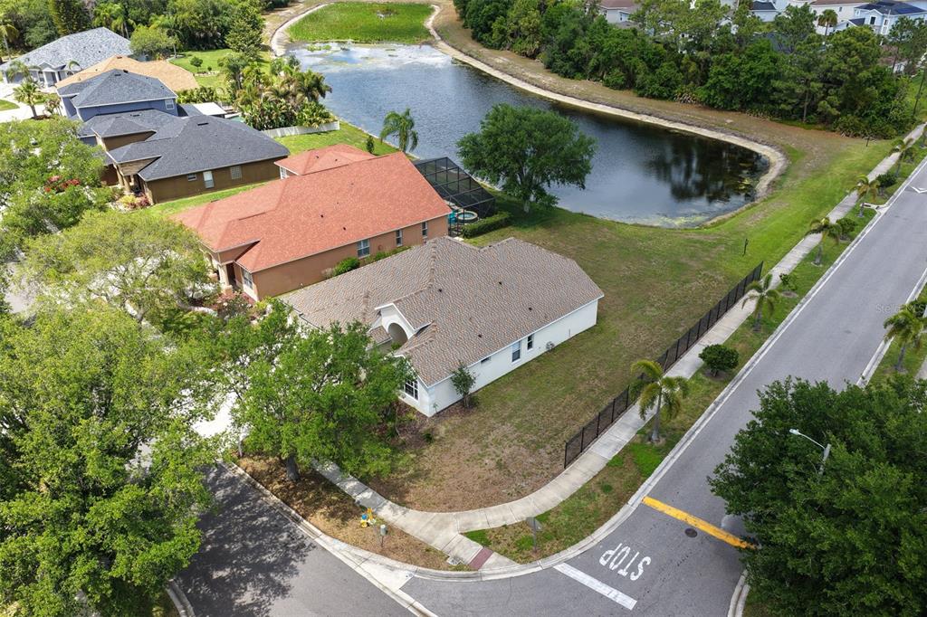 An aerial view shows a suburban house with a brown roof near a pond — 9103 PINEBREEZE DRIVE, RIVERVIEW, FL