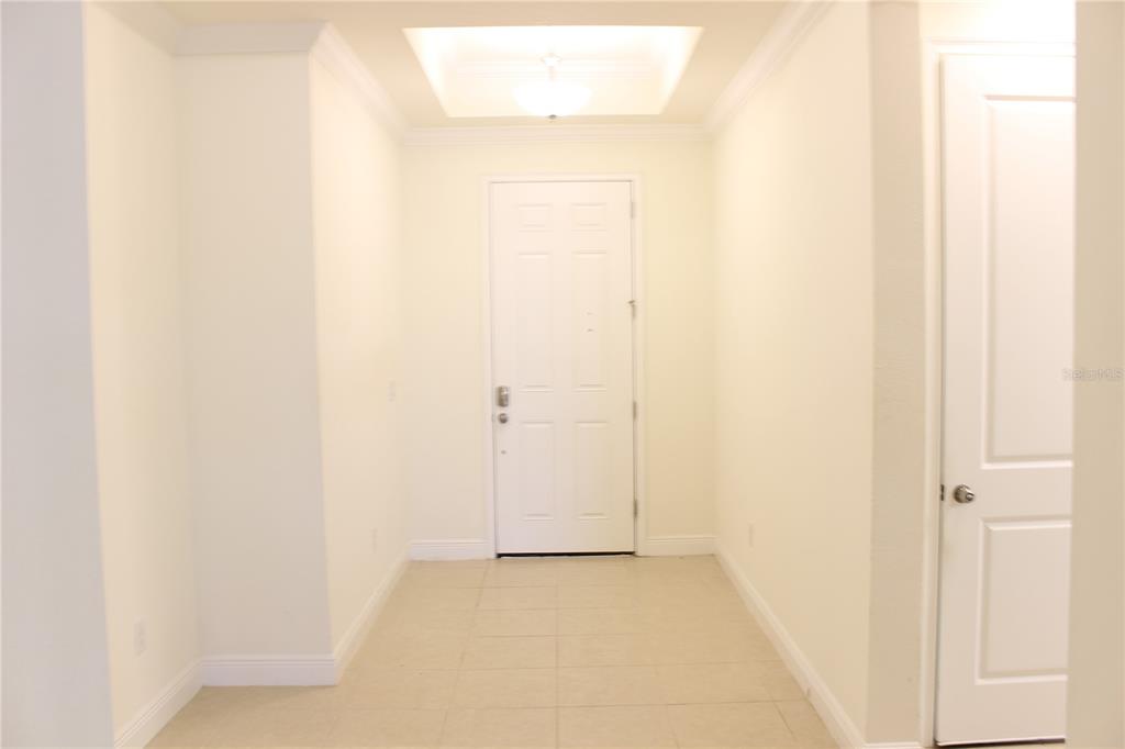 An entryway features a white front door, tile flooring, and a recessed ceiling light — 5826 LONG SHORE LOOP, SARASOTA, FL