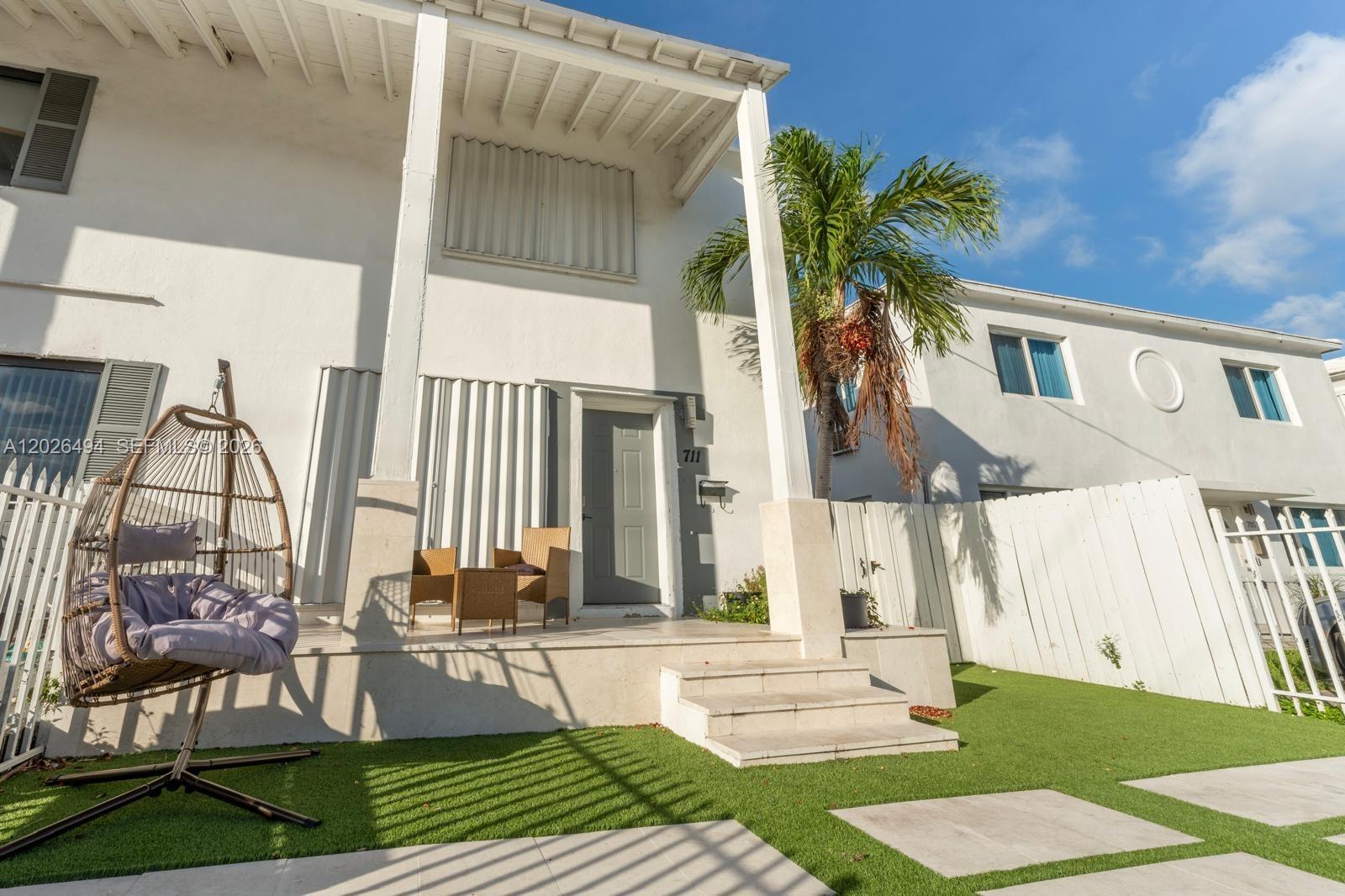 A white two-story house features a front porch with a hanging chair and artificial turf — 711 85th St, Miami Beach FL 33141, MIAMI BEACH, FL