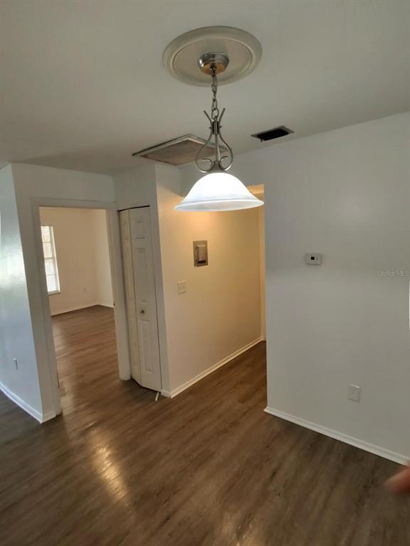 A room with wood-look flooring, a pendant light fixture, and a white bi-fold closet door — 6008 VILLAGE CIRCLE UNIT GE, ORLANDO, FL