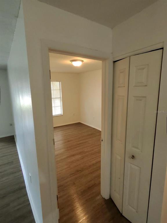 A view through a doorway into a bedroom with wood-look flooring and a window — 6008 VILLAGE CIRCLE UNIT GE, ORLANDO, FL